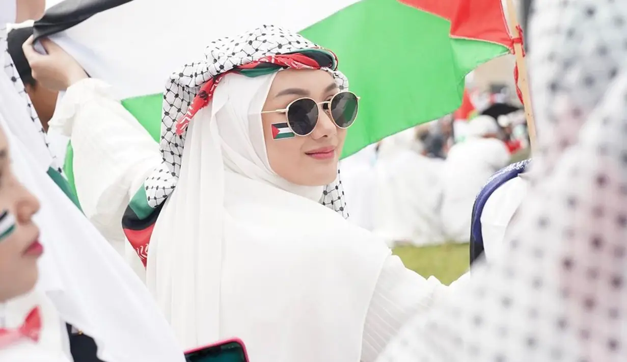 Dinda Hauw adalah salah satu artis yang ikuti dalam aksi bela Palestina di Monas. Pakai jilbab putih, kenakan sorban Palestina, dan wajah dipoles dengan makeup natural, penampilan Dinda Hauw ini sederhana dan tidak neko-neko. Namun rupanya ada netizen yang permasalahkan penampilan Dinda dan ekspresi wajahnya. Gara-gara senyum, Dinda dituding tidak merasakan sedih karena kejadian di Gaza. (Liputan6.com/IG/@dindahw)