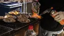 Seorang penjual menggunakan obor untuk makanan laut segar di area "pasar ikan luar" Tsukiji di Tokyo pada 28 Desember 2022. Menjelang liburan Tahun Bar, turis asing dan penduduk lokal berkunjung  ke pasar itu untuk menikmati hidangan bermacam makanan laut. (AFP/Richard A. Brooks)