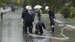 Pekerja memeriksa lubang drainase di alun-alun saat Topan Hinnamnor bergerak menuju Semenanjung Korea di Seoul, Korea Selatan, Senin (5/9/2022). Peringatan hujan lebat telah dikeluarkan untuk semua wilayah di Korea Selatan hingga hari Selasa. (AP Photo/Lee Jin-man)