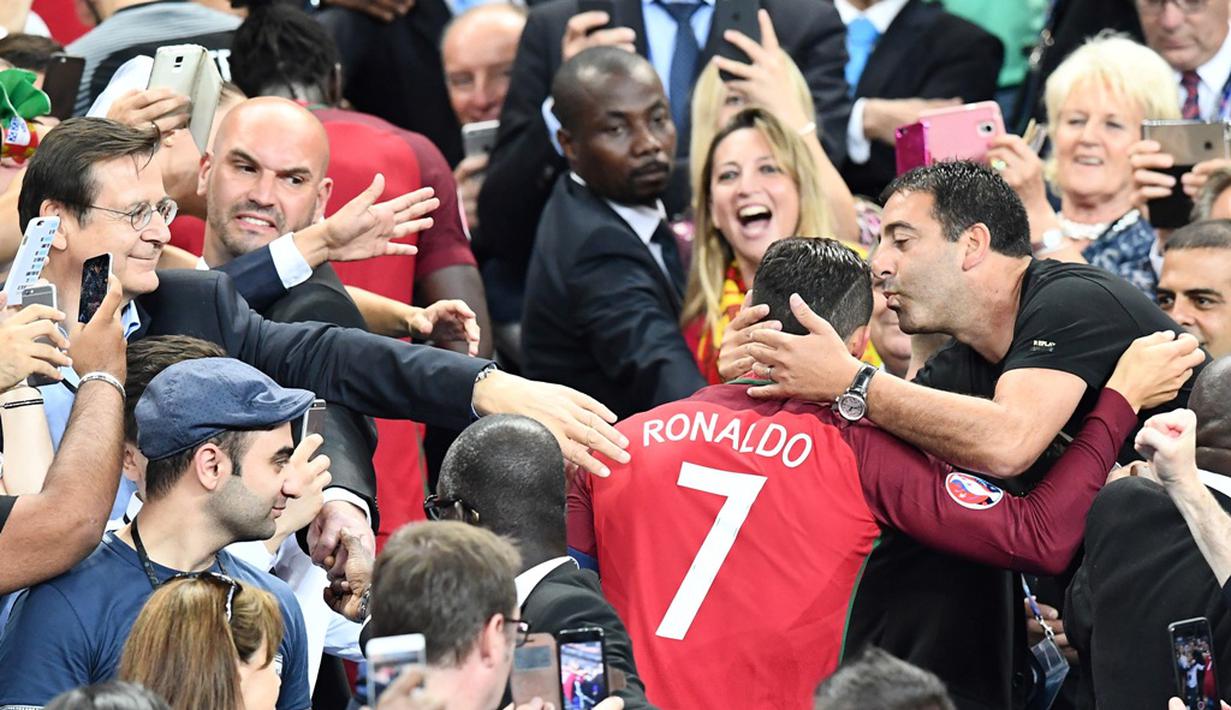 Striker Portugal, Cristiano Ronaldo, dipeluk seorang pendukung Portugal setelah meraih gelar juara Piala Eropa 2016 di Stade de France, Saint-Denis, Senin (11/7/2016) dini hari WIB. (AFP/Franck Fife)