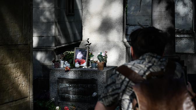 Seorang pria melihat makam almarhum bintang rock AS Jim Morrisson di pemakaman Pere Lachaise selama di Paris (22/7/2019). Pemakaman ini dibuka pada tahun 1804. (AFP Photo/Philippe Lopez)