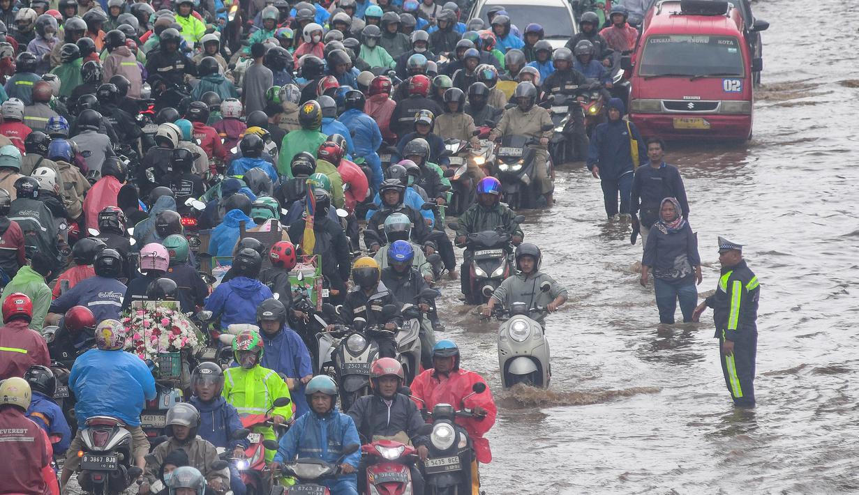 Sejumlah pengendara roda dua yang nekat menerjang genangan banjir mengalami mogok sehingga terpaksa menepi ke pinggir jalan. Tampak dalam foto, antrean pengendara motor yang mencoba menerobos banjir di Jalan Daan Mogot, Jakarta, Jumat (23/1/02026). (merdeka.com/ Arie Basuki)