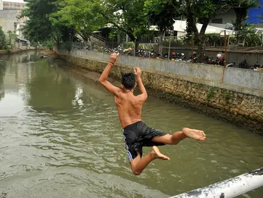 Kondisi air pada Anak Sungai Ciliwung di Jalan Labu, Kelurahan Mangga Besar sudah mulai membaik, Jakarta, Selasa (17/5). Meski belum terlalu bersih, seorang anak terlihat melompat untuk berenang di sungai tersebut. (Liputan6.com/Gempur M Surya)