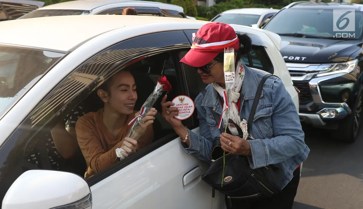 Relawan Jokowi saat membagikan bunga mawar di Kawasan Sarinah, Jakarta, Minggu (29/9/2019). Aksi bagi bunga tersebut merupakan aksi damai kami bersama Jokowi. (Liputan6.com/Angga Yuniar)