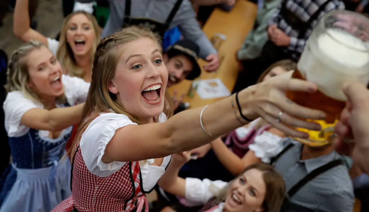 Seorang wanita mengambil gelas bir selama pembukaan festival bir Oktoberfest di 184, Munich, Jerman, (16/9). Festival ini diadakan dari tanggal 16 sampai 3 Oktober 2017. (AP Photo / Matthias Schrader)