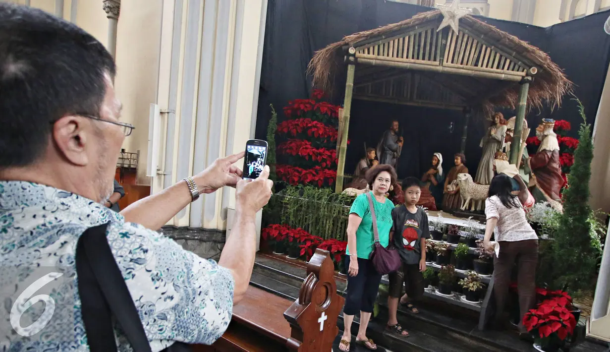 Pengunjung berfoto didekat diorama kelahiran Yesus Kristus di Gereja Katedral, Jakarta (23/12). Jelang perayaan Natal, Gereja Katedral mulai berhias dengan berbagai ornamen, salah satunya diorama kelahiran Yesus Kristus. (Liputan6.com/Immanuel Antonius)
