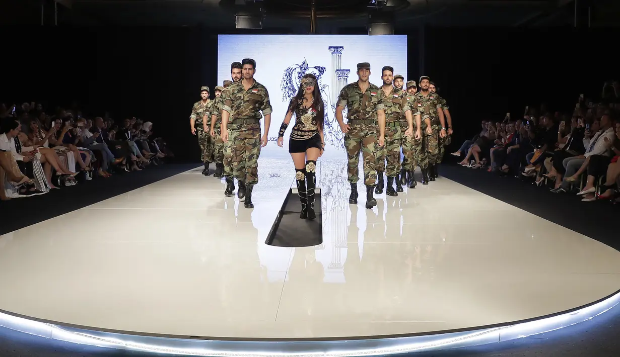 Perancang busana Suriah, Manal Ajaj (tengah) berjalan di atas catwalk bersama model pria yang mengenakan seragam tentara Suriah di Beirut (11/10). (AFP Photo/Joseph Eid)
