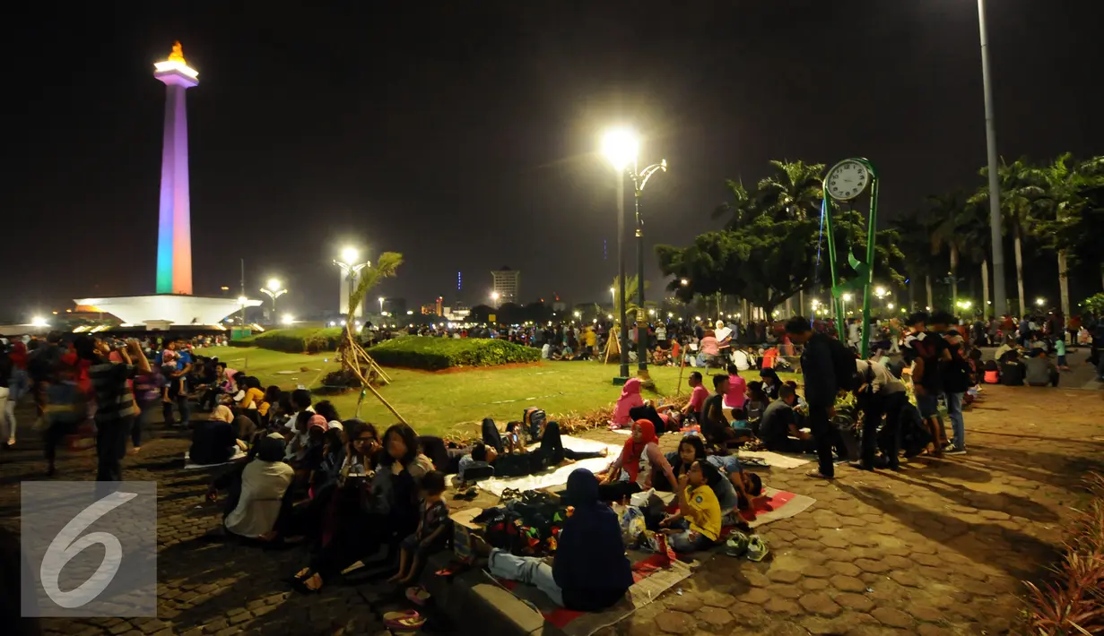 Pengunjung duduk duduk di halaman Monumen Nasional, Jakarta, Sabtu (31/12). Dengan alasan keamanan, Pemprov DKI Jakarta membatalkan panggung hiburan malam pergantian tahun di kawasan Monumen Nasional. (Liputan6.com/Helmi Fithriansyah)