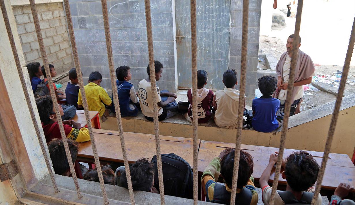 Anak-anak Yaman menghadiri kelas di luar ruangan sebuah sekolah yang rusak parah pada hari pertama tahun ajaran baru di provinsi barat Yaman yang dilanda perang Hodeida, Senin (17/10/2022). UNICEF memperkirakan bahwa lebih dari dua juta anak telah putus sekolah di Yaman, peningkatan hampir setengah juta sejak perang pecah pada 2015. (Foto oleh Khaled ZIAD / AFP).