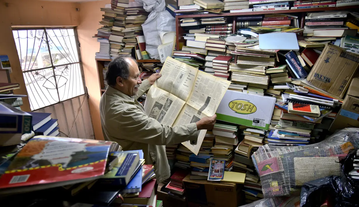 Jose Alberto Gutierrez membaca koran tua di antara koleksi buku di perpustakaan rumahnya di Bogota, 18 Mei 2017. Meski awalnya Gutierrez menemukan buku dari tumpukan sampah, sebagian besar buku yang ia koleksi kini adalah sumbangan (GUILLERMO LEGARIA/AFP)