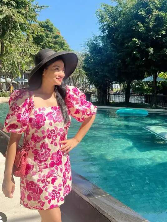 Tampil lebih feminim dengan mini dress pink motif bunga besar dengan aksen lengan puffnya. [@titi_kamall]