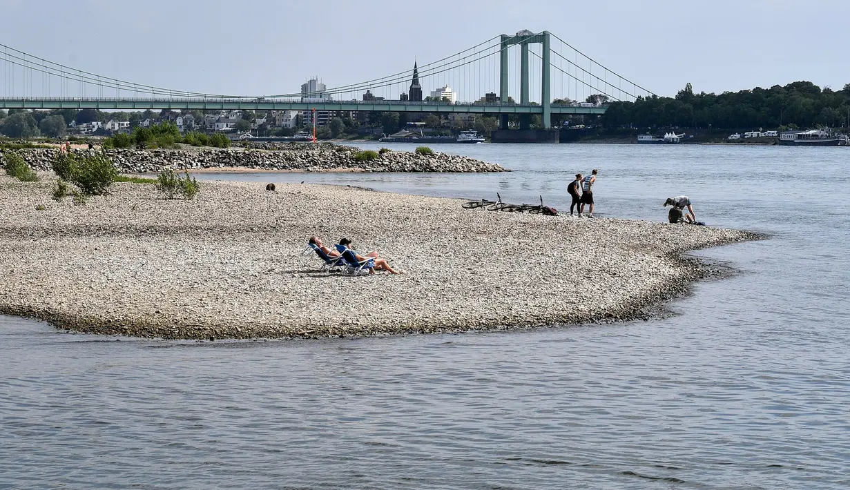 Orang-orang menikmati cuaca cerah di tepi sungai Rhine yang mengering akibat kemarau panjang di Cologne, Jerman pada 27 April 2020. April tahun ini adalah salah satu bulan terkering dan berimbas kepada petani dan industri. (AP/Martin Meissner)