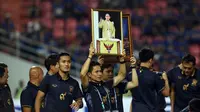 Pemain Timnas Thailand mengangkat foto Sang Raja saat menyambut kemenangan atas Indonesia di National Stadium Rajamangala, Bangkok, Sabtu (17/12). Thailand berhasil meraih piala AFF untuk yang kelima kali. (Liputan6.com/HelmiFithriansyah)