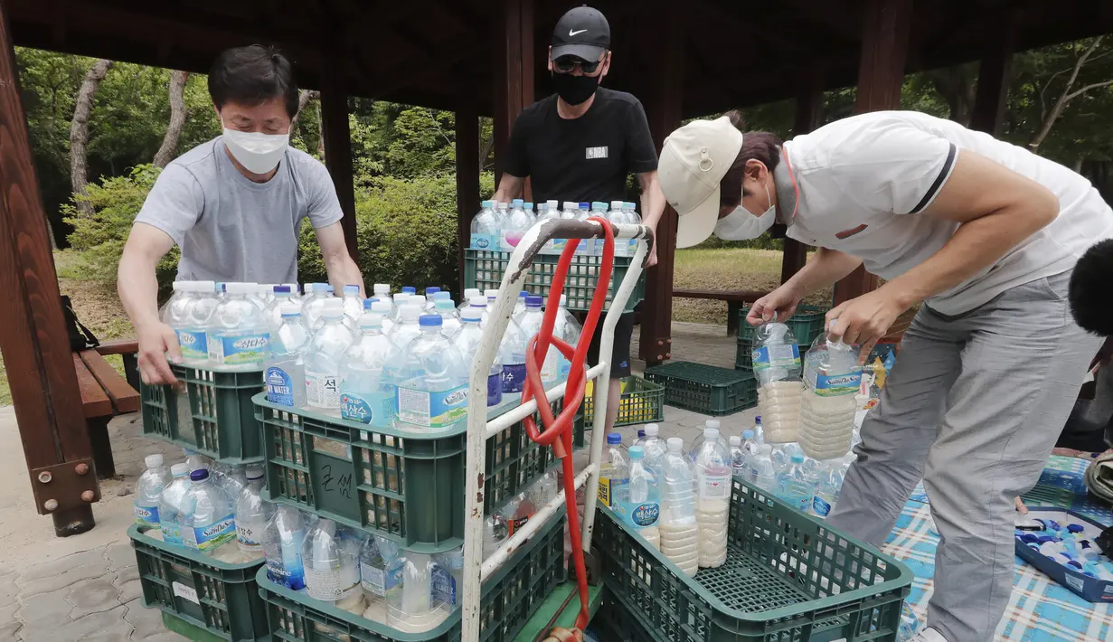 Para pembelot Korea Utara membawa botol-botol plastik berisi beras dan masker untuk dikirim ke Korea Utara menggunakan balon, Seoul, Korea Selatan, Kamis (18/6/2020). Kementerian Unifikasi Korea Selatan mengumumkan akan mengambil langkah hukum atas tindakan para pembelot. (AP Photo/Ahn Young-joon)