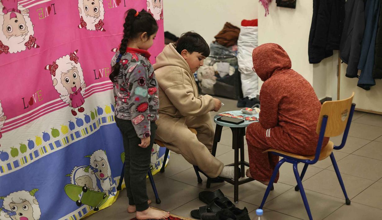 Banyak pengungsi terpaksa menumpang di rumah kerabat atau tinggal di dalam kendaraan, membuat momen Ramadan 1477 Hijriah dilakukan dalam kondisi penuh keprihatinan. Tampak dalam foto, anak-anak pengungsi yang tinggal bersama keluarga mereka di ruang kelas sekolah, setelah melarikan diri dari serangan udara Israel di pinggiran selatan Beirut, Lebanon, duduk untuk berbuka puasa bersama, pada 7 Maret 2026. (Ibrahim AMRO/AFP)