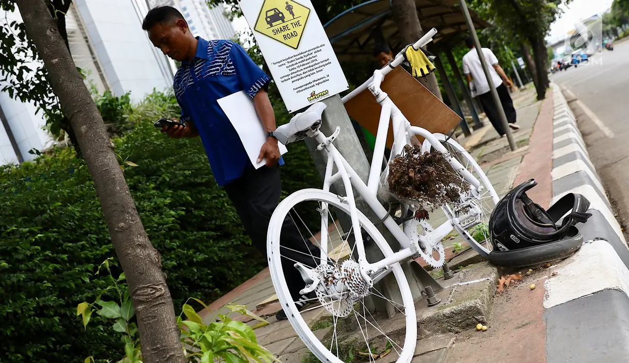 Pejalan kaki melintasi monumen sepeda putih di sebuah tiang kawasan Jenderal Gatot Subroto, Jakarta, Senin (12/3). Monumen itu sebagai peringatan kepada pengguna jalan untuk saling berbagi dan menghormati di jalan. (Liputan6.com/Immanuel Antonius)
