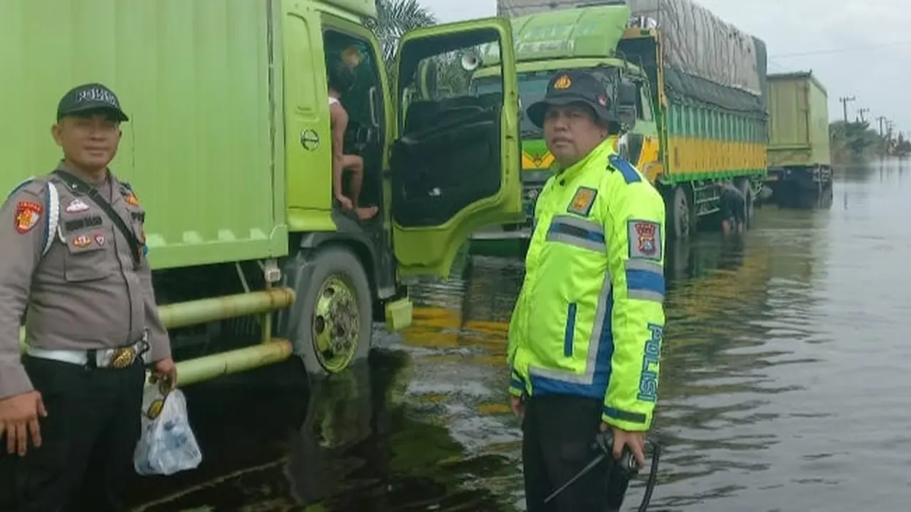 Personel Polres Pelalawan mengamankan jalur di Jalan Lintas Timur kilometer 83 karena terendam banjir.
