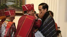 Pemangku Hutan Adat dari Tombak Haminjon (Kemenyan) Provinsi Sumatera Utara mengalungkan kain ulos kepada Presiden Joko Widodo (Jokowi) usai pencanangan pengakuan Hutan Adat di Istana Negara, Jakarta, Jumat (30/12). (Liputan6.com/Faizal Fanani)