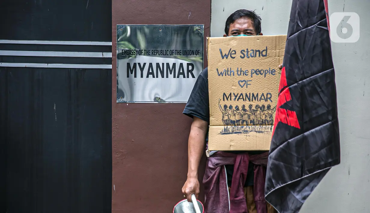 Massa Leader and Organizer of Community Organization in Asia ( LOCOA) menunjukkan kardus bertuliskan "We Stand with the People of Myanmar" saat menggelar aksi damai di depan Kedutaan Besar Myanmar, Jakarta, Jumat (5/2/2021). Massa mengecam mundurnya demokrasi di Myanmar. (Liputan6.com/Faizal Fanani)
