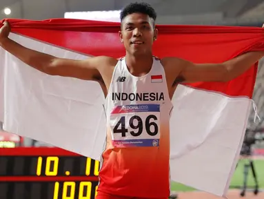 Sprinter Indonesia, Lalu Muhammad Zohri mengibarkan bendera Merah Putih seusai mengikuti kategori 100 meter dalam semifinal Kejuaraan Atletik Asia di Doha, Qatar, Senin (22/4/2019). Lalu Muhammad Zohri sukses menggondol medali perak setelah membukukan catatan waktu 10,13 detik. (AP/Vincent Thian)