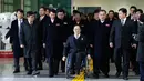 Direktur Komite Paralimpiade Pyeongchang 2018, Lim Chan-kyu (tengah) mengawal delegasi Korea Utara saat mereka tiba di Kantor Transit Korea, dekat Zona Demiliterisasi, Paju, Korea Selatan, Rabu (7/3). (Ahn Young-joon/POOL/AFP)