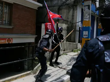 Seorang polisi Nepal memungkul pakai tongkat seorang pemuda saat protes di dekat kediaman perdana menteri menuntut penanganan yang lebih baik terhadap pandemi COVID-19 di Kathmandu, Nepal (11/6/2020).  (AP Photo/Niranjan Shrestha)