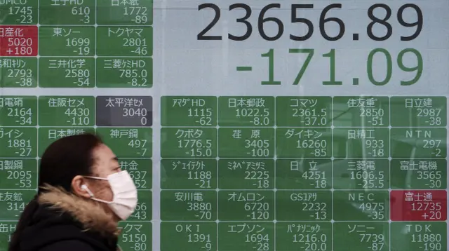 Seorang wanita berjalan melewati layar monitor yang menunjukkan indeks bursa saham Nikkei 225 Jepang dan lainnya di sebuah perusahaan sekuritas di Tokyo, Senin (10/2/2020). Pasar saham Asia turun pada Senin setelah China melaporkan kenaikan dalam kasus wabah virus corona. (AP Photo/Eugene Hoshiko)