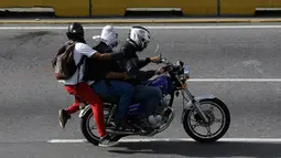 Tiga demonstran berada di motor saat terjadi bentrokan dengan pasukan keamanan di Caracas, Venezuela, (31/5). Aksi besar di Venezuela ini merupakan kelanjutan untuk melawan Maduro. (AP Photo/Fernando Llano)