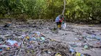 Seorang relawan dari Ecological Observation and Wetlands Conservation (ECOTON) mengumpulkan sampah plastik dari rawa bakau di Surabaya, Jawa Timur pada 26 Juli 2025. (Juni KRISWANTO/AFP)