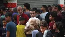 Seorang pria Palestina membawa kantong-kantong roti setelah menerima bantuan dari toko roti amal di kamp pengungsi Nuseirat, yang terletak di Jalur Gaza tengah, pada 2 November 2025. Bantuan tersebut mencakup makanan, obat-obatan, suplemen gizi, serta bahan untuk tempat tinggal. (EYAD BABA/AFP)