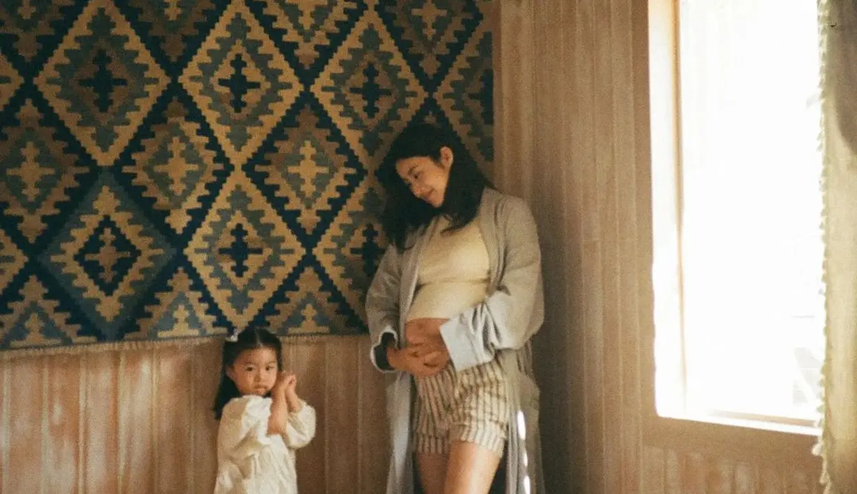 Dengan t-shirt putih dan celana pendek bergaris dan long outer, Kang Sora didampingi putrinya yang kenakan dress tidur putih [@reveramess_]