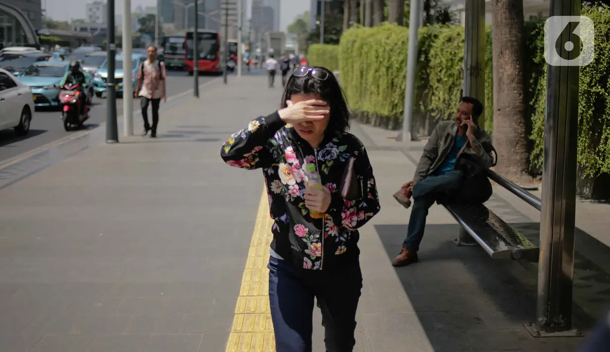 Seorang wanita menutupi wajahnya selama gelombang panas di Jakarta, Selasa (22/10/2019).  BMKG memprediksi wilayah Indonesia akan mengalami panas selama kurang lebih satu minggu ini. Hal ini dikarenakan matahari yang berada dekat dengan jalur khatulistiwa. (Liputan6.com/Faizal Fanani)