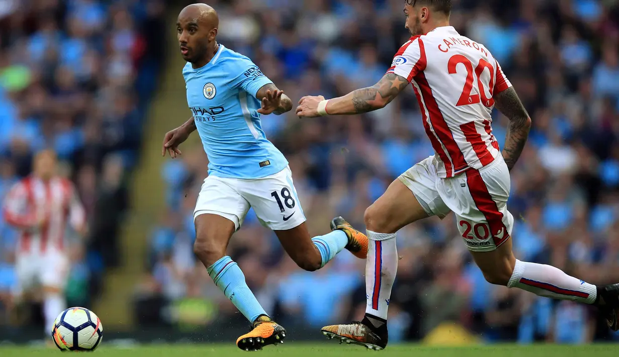 Gelandang Manchester City, Fabian Delph berusaha membawa bola dari kawalan pemain Stoke City, Geoff Cameron saat bertanding pada lanjutan Liga Inggris di Etihad Stadium, Manchester, (14/10). City menang 7-2 atas Stoke. (Mike Egerton / PA via AP)