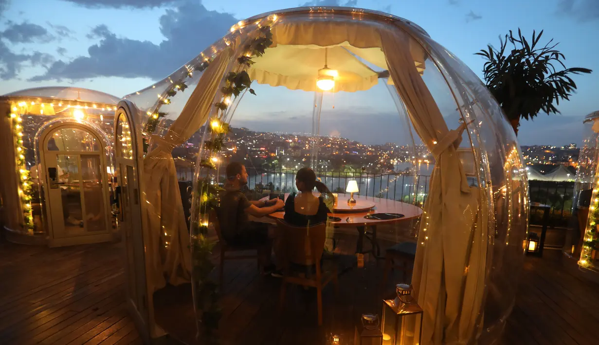 Para pelanggan menikmati makan malam mereka di zona aman yang disediakan sebuah restoran di Istanbul, Turki (16/6/2020). Terlihat seperti stoples transparan, restoran ini sepenuhnya terlindung dan steril dari COVID-19. (Xinhua/Osman Orsal)