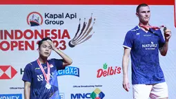 Ekspresi tunggal putra Indonesia, Anthony Ginting (kiri), di atas podium bersama Viktor Axelsen, setelah laga final Indonesia Open 2023 di Istora Gelora Bung Karno, Jakarta, Minggu (18/6/2023). (Bola.com/M Iqbal Ichsan)