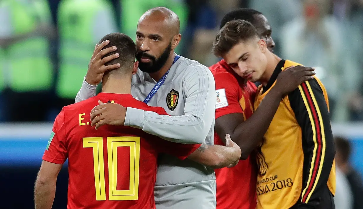 Asisten pelatih Belgia, Thierry Henry menghibur Eden Hazard pada akhir babak semifinal Piala Dunia 2018 melawan Prancis di Stadion St. Petersburg, Selasa (10/7). Upaya Belgia tampil di final berakhir usai takluk 0-1 dari Prancis. (AP/Petr David Josek)