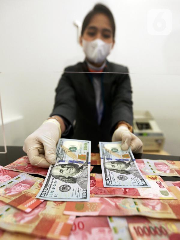 Karyawan menunjukkan uang dolar AS dan rupiah di Jakarta, Rabu (30/12/2020). Nilai tukar rupiah di pasar spot ditutup menguat 80 poin atau 0,57 persen ke level Rp 14.050 per dolar AS. (Liputan6.com/Johan Tallo)