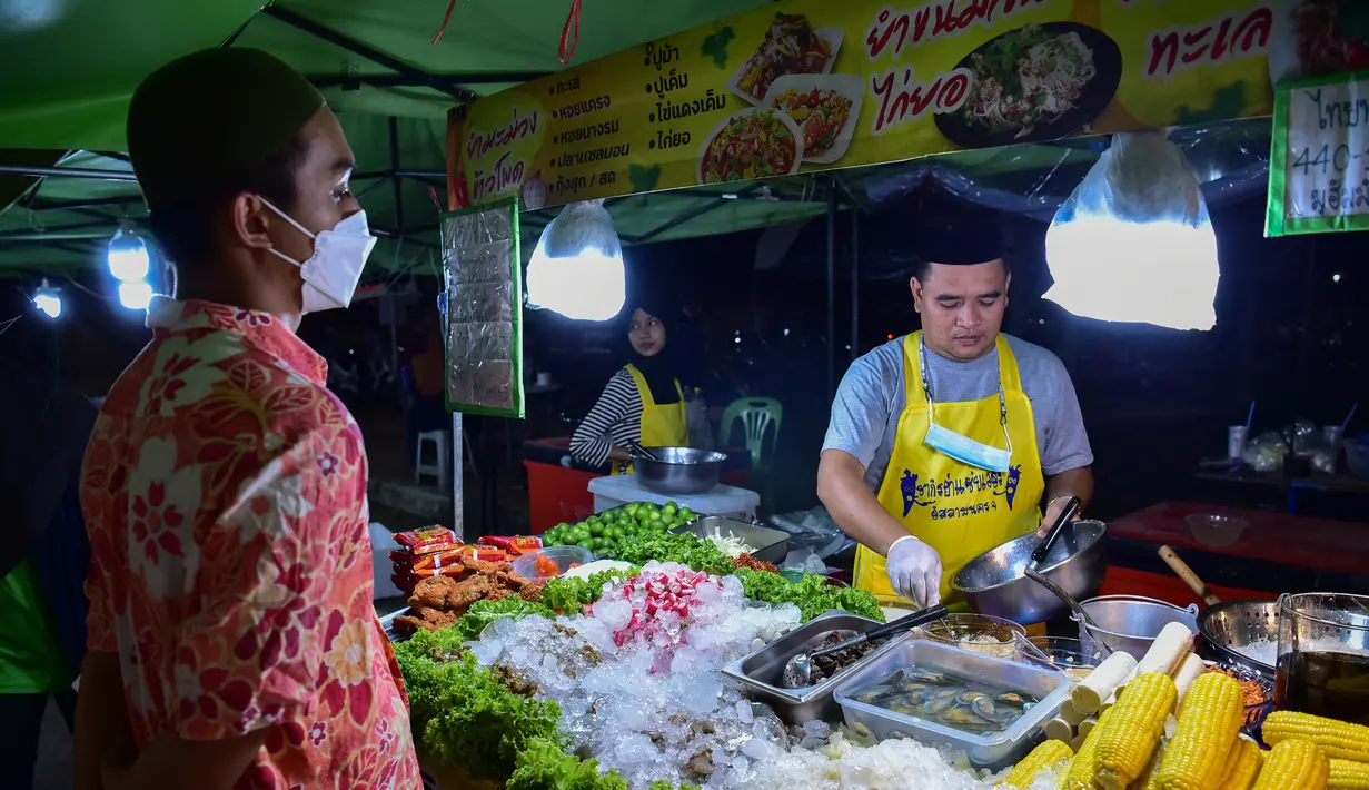 <p>Penjual membuat makanan untuk pembeli  selama bulan suci Ramadhan di pasar malam di provinsi Narathiwat, Thailand selatan (21/4/2022). Penjual makanan jalanan mendirikan kios mereka untuk menjual makanan kepada umat Muslim untuk berbuka puasa. (AFP/Madaree Tohlala)</p>