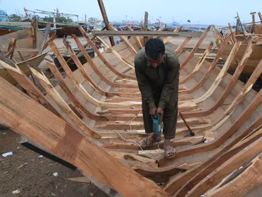 Tukang kayu Pakistan membuat kapal penangkap ikan di sebuah pelabuhan di Karachi (3/4). Pembuatan kapal buatan Pakistan menghasilkan ratusan kapal setiap tahun untuk memenuhi permintaan industri perikanan setempat. (AFP Photo/Asif Hassan)