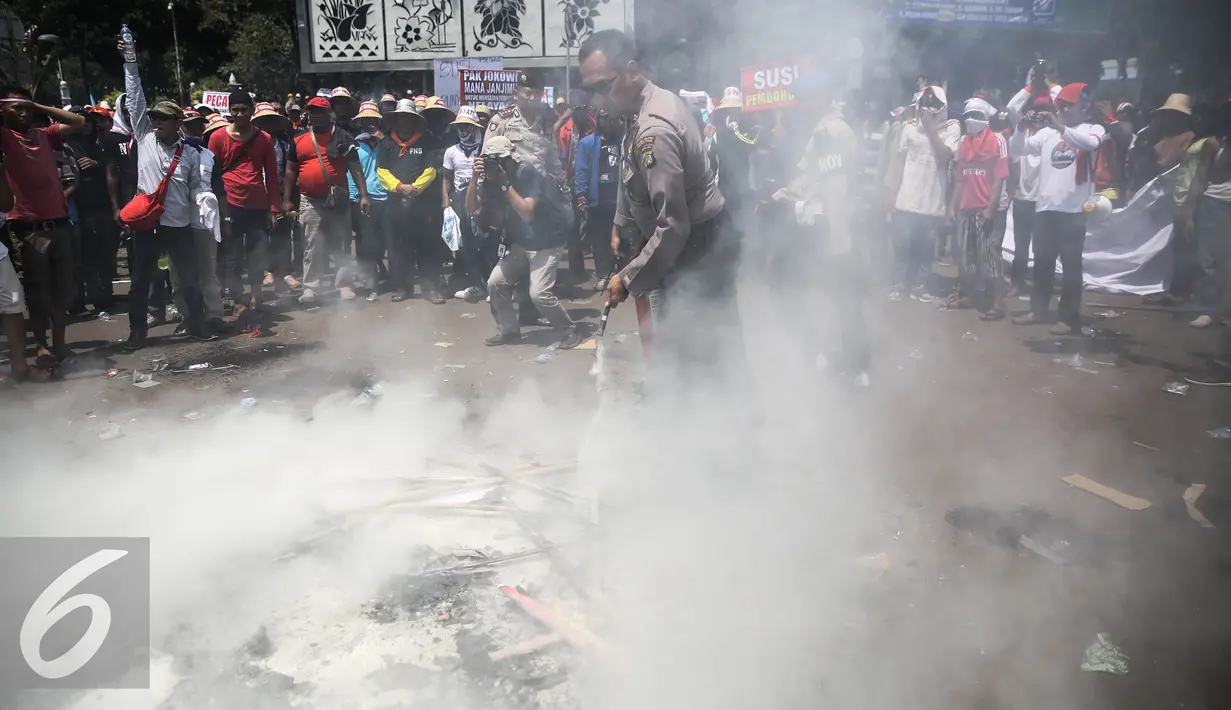 Petugas memadamkan atribut yang dibakar oleh massa saat aksi berlangsungnya unjuk rasa memperingati hari Nelayan Nasional didepan Istana Merdeka, Jakarta, Rabu (6/4). (Liputan6.com/Faizal Fanani)