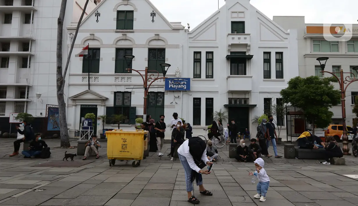 Pengunjung memotret anaknya di kawasan wisata Kota Tua Jakarta, Minggu (4/4/2021). Libur panjang perayaan Paskah 2021 dimasa pemberlakuan PPKM Berskala mikro dimanfaatkan sejumlah warga untuk berwisata di kawasan Kota Tua Jakarta. (Liputan6.com/Helmi Fithriansyah)