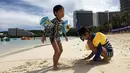 Anak-anak bermain pasir di pantai Tumon, Guam, Kamis (10/8). Meskipun suasana ketegangan di kawasan itu meningkat terkait ancaman bom nuklir Korea Utara, warga Guam tetap beraktivitas seperti biasa. (AP Photo/Tassanee Vejpongsa)