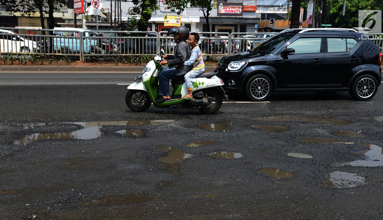 Pengendara mobil dan sepeda motor menghindari jalan yang ruas saat melintasi ruas Jalan Lapangan Ros, Tebet, Jakarta, Sabtu (11/5/2019). Jalan-jalan berlubang yang terisi air tersebut dapat mengakibatkan kecelakaan bagi pengendara kendaraan bermotor. (merdeka.com/Imam Buhori)