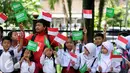 Sejumlah pelajar mengibarkan bendera kedua negara untuk menyambut kedatangan Raja Salman bin Abdulaziz di Istana Bogor, Rabu (1/3). 21 dentuman meriam dan kibaran bendera kedua negara mewarnai sambut Raja Salman. (Liputan6.com/Helmi Fithriansyah)