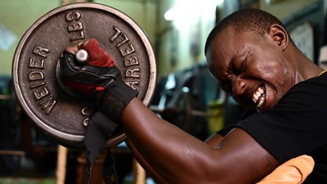 Seorang binaragawan mengangkat beban saat berolahraga di gym Kaloleni, di Nairobi, Kenya (9/1). (AFP Photo/Simon Maina)