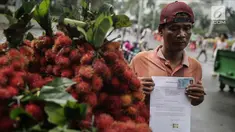 Seorang pedagang buah rambutan menunjukkan surat pernyataan saat ditindak oleh Petugas Dinas Perhubungan di Car Free Day (CFD) di kawasan Bunderan HI, Jakarta, Minggu (4/2). (Liputan6.com/Faizal Fanani)