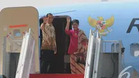 Presiden Jokowi dan Iriana melambaikan tangan dari tangga pesawat Kepresiden RI. 