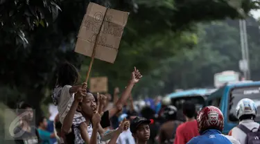 Sejumlah anak membawa spanduk pesan Om Telolet Om agar pengemudi bus membunyikan klakson di Jalan Raya Bogor, Jakarta, Sabtu (24/12). Libur sekolah dimanfaatkan anak-anak untuk berburu bus yang membunyikan klakson telolet. (Liputan6.com/Faizal Fanani)