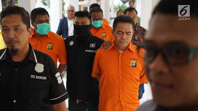 Tokoh pemuda Umar Kei (kanan) digelandang petugas saat rilis kasus narkotika jenis sabu di Polda Metro Jaya, Jakarta, Kamis (15/8/2019). Polisi menyita 2,91 gram sabu, senjata api revolver dengan enam butir peluru, alat hisap sabu, sebuah mobil, serta empat unit HP. (Liputan6.com/Immanuel Antonius)