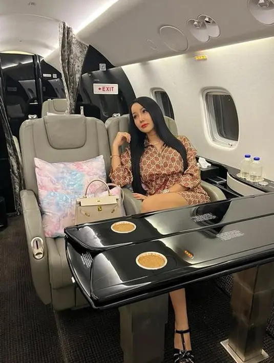 Berpose duduk di salah satu kursi penumpang pesawat jet, Lucinta Luna tampil dalam balutan outfit mewah. Memadukan dress dengan outfit menarik, dan sepasang strap heels warna hitam.(instagram.com/lucintaluna_manjalita)